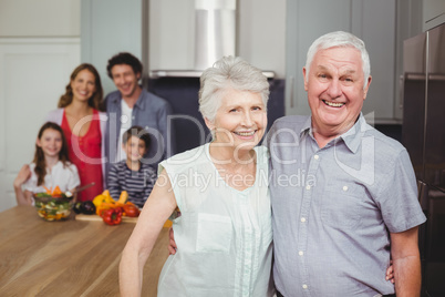 Portrait of smiling grandparents with family in kitchen
