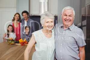 Portrait of smiling grandparents with family in kitchen