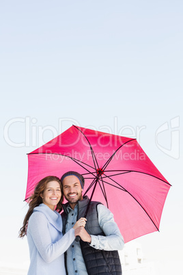 Happy young couple holding pink umbrella