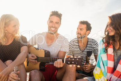 Happy friends having fun while sitting on sand