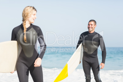 Couple with surfboard walking on the beach