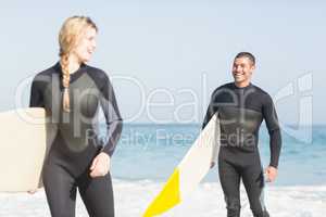 Couple with surfboard walking on the beach
