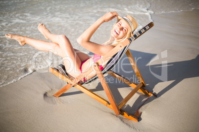Happy woman relaxing on an armchair on the beach
