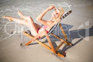 Happy woman relaxing on an armchair on the beach