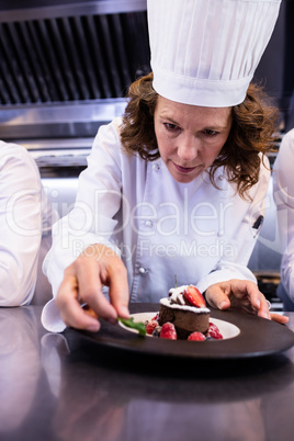 Female chef garnishing a dessert with a mint leaf