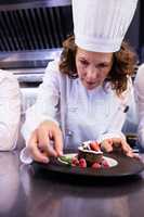 Female chef garnishing a dessert with a mint leaf