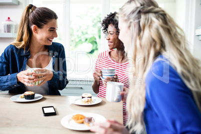 Cheerful young female friends having breakfast