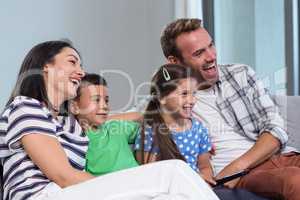 Happy young family watching television with their two children