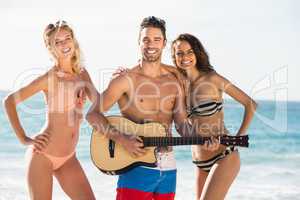 Happy friends posing and playing guitar on the beach