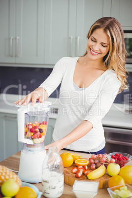 Smiling woman using juicer at table