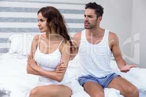 Husband arguing with wife while sitting on bed