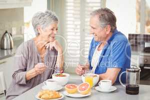 Happy senior couple discussing while having breakfast