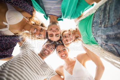 Group of friends forming a huddle against sky