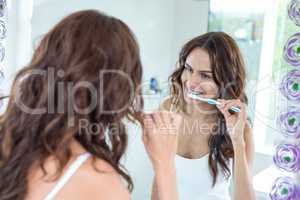 Woman brushing teeth while looking in mirror