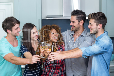 Multi-ethnic friends toasting beer and wine in kitchen