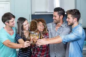 Multi-ethnic friends toasting beer and wine in kitchen