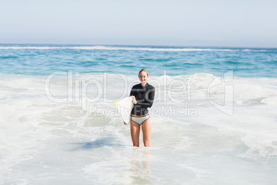 Woman in wetsuit holding a surfboard on the beach