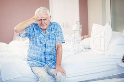 Suffering senior man holding his head st home