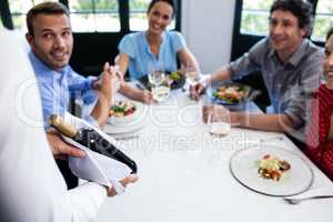 Waiter carrying a wine bottle for a group of friends