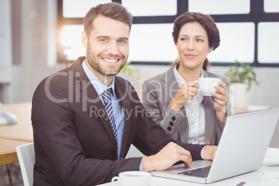 Confident businessman with female colleague in office