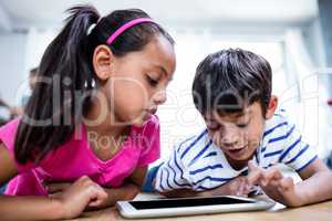 Brother and sister lying on floor and using digital tablet