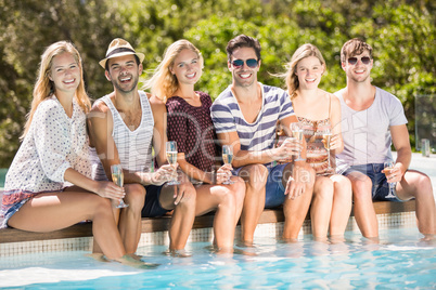 Group of friends sitting at poolside with glass of champagne