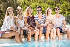 Group of friends sitting at poolside with glass of champagne
