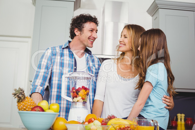 Happy family preparing fruit juice at table