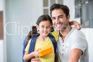 Portrait of smiling father and daughter with lunch box