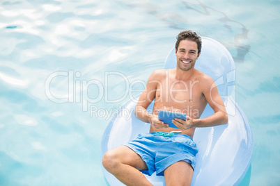 Shirtless man using digital tablet on inflatable ring