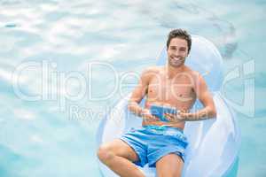 Shirtless man using digital tablet on inflatable ring