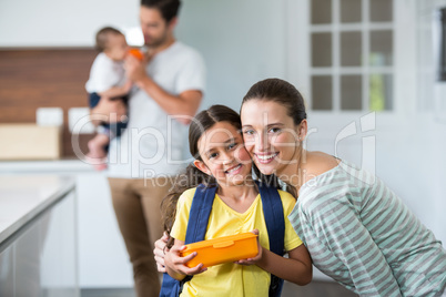 Portrait of smiling mother and daughter holding lunch box