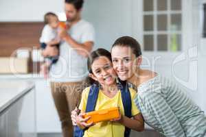 Portrait of smiling mother and daughter holding lunch box