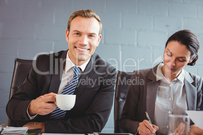 Businessman holding cup and smiling at camera