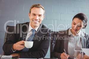 Businessman holding cup and smiling at camera