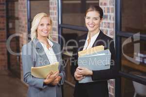 Portrait of smiling businesswomen holding documents