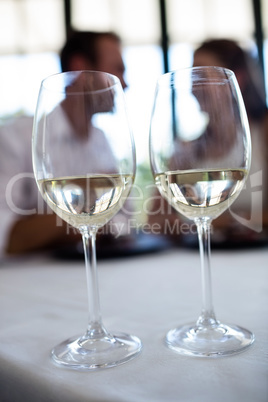 Close up of two wine glasses and couple in background