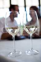 Close up of two wine glasses and couple in background