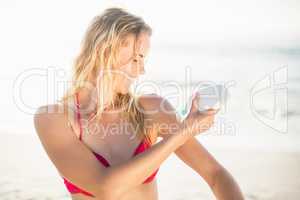 Woman applying sunscreen lotion on the beach