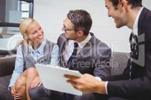 Smiling businesman with clients sitting on sofa