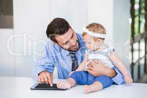 Businessman showing digital tablet to daughter