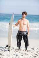 Happy man holding a surfboard on the beach