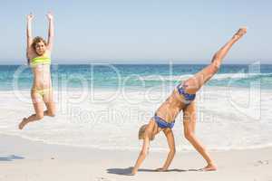 Two women jumping on the beach