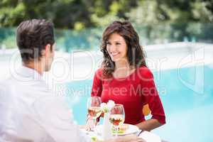 Smiling couple sitting by swimming pool