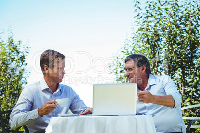 Casual businessmen having coffee and using laptop