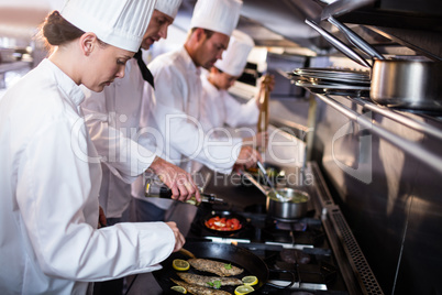 Chef frying fish in a frying pan