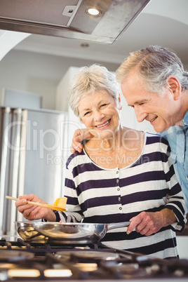 Happy senior couple cooking food in kitchen