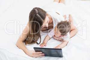 Mother using tablet PC while holding baby at home