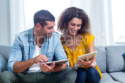 Young couple using a digital tablet on sofa