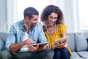 Young couple using a digital tablet on sofa